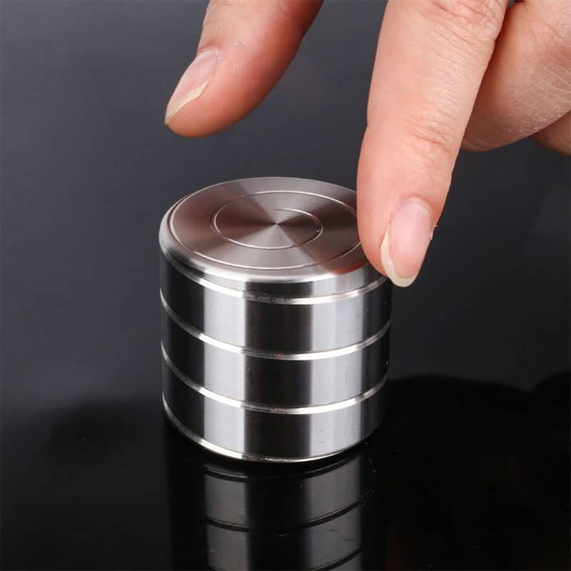 Dispositivo scientifico in metallo con superficie liscia e cilindri sovrapposti, utilizzato in esperimenti di laboratorio o decorazioni a tema scientifico.