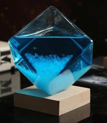 Vaso di cristallo trasparente con liquido blu e cristalli di sale, posizionato su base di legno, decorazione scientifica elegante e moderna.