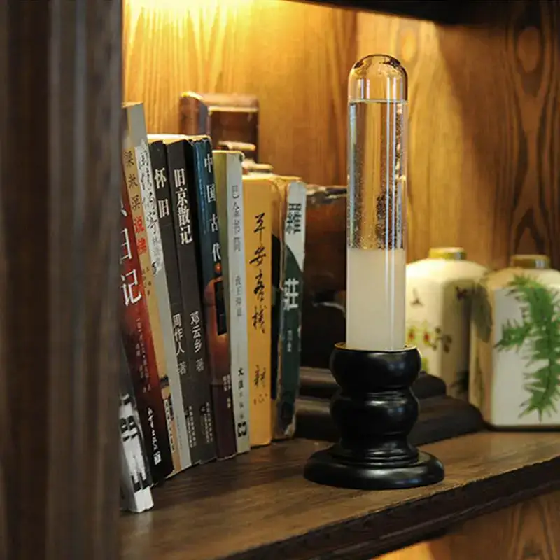 Oggetto decorativo scientifico in vetro con bolle e liquido, posizionato su mensola di legno, tra libri e oggetti d'arredo.