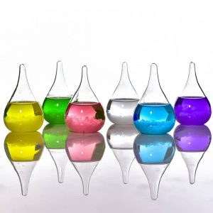 Vasi di vetro colorati con liquidi di diversi colori, riflessi su superficie lucida, decorazioni scientifiche e artistiche.