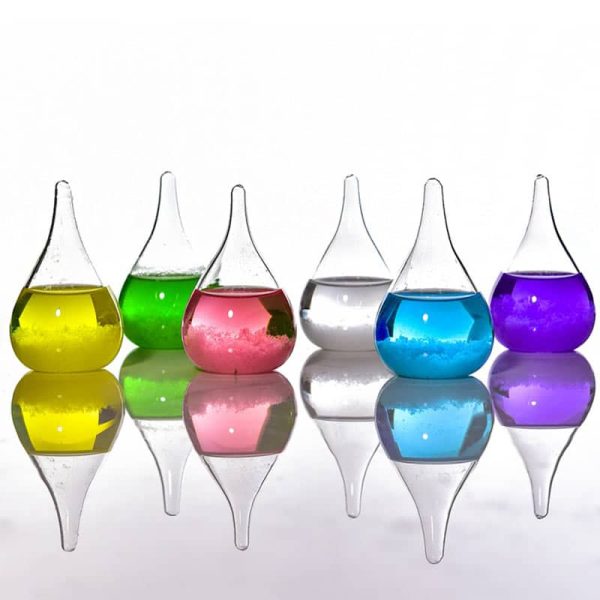 Vasi di vetro colorati con liquidi di diversi colori, riflessi su superficie lucida, decorazioni scientifiche e artistiche.