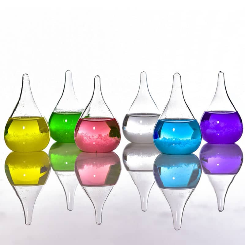 Vasi di vetro colorati con liquidi di diversi colori, riflessi su superficie lucida, decorazioni scientifiche e artistiche.