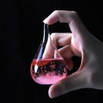 Provetta con liquido rosa e bolle, esperimento scientifico in laboratorio.