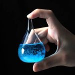 Provetta con liquido blu brillante, utilizzata in esperimenti scientifici di chimica, tenuta tra le dita di una mano.