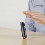 Penna laser scientifica in equilibrio su una superficie, con una mano che la sostiene, simbolo di precisione e innovazione scientifica.