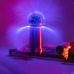 Modello di esperimento scientifico con pallone di Tesla che genera scariche elettriche blu, illuminando l'ambiente circostante con effetti luminosi spettacolari.