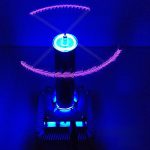 Vaso di Tesla che crea scariche elettriche blu e arancioni in un ambiente scuro, con effetti luminosi che evidenziano le scariche elettriche e le onde di energia.