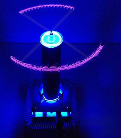 Vaso di Tesla che crea scariche elettriche blu e arancioni in un ambiente scuro, con effetti luminosi che evidenziano le scariche elettriche e le onde di energia.