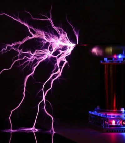 Scarica elettrica visibile con fulmini viola in laboratorio, con apparecchiature scientifiche e generatori di Tesla.