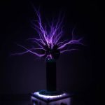 Modello di pila di Tesla con scariche di plasma viola che si irradiano verso l'alto, creando un effetto visivo impressionante e futuristico.