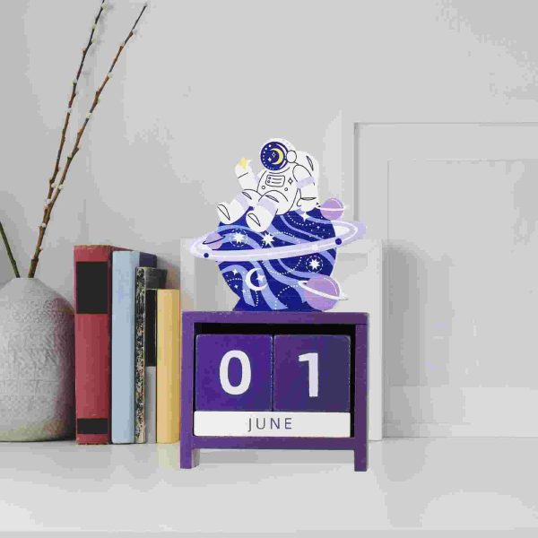 Decorazione di un astronauta in miniatura su un calendario a blocchi con data 1 giugno, con sfondo minimalista e libri, ideale come decorazione scientifica.