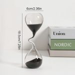 Orologio a sabbia trasparente con sabbia nera, design elegante e contemporaneo, altezza 18,5 cm, perfetto come decorazione scientifica e da scrivania.