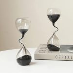 Orologio a clessidra decorativa in vetro con sabbia nera, perfetta come oggetto di design e decorazione scientifica.