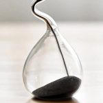 Vaso di vetro trasparente con pipetta e sabbia nera, oggetto decorativo scientifico elegante e moderno.