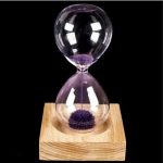 Orologio a sabbia scientifico con base in legno e sabbia viola, perfetto come decorazione educativa e da scrivania. Design elegante e funzionale per appassionati di scienza.