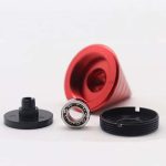 Componenti di un oggetto scientifico con contenitore rosso, cuscinetto a sfera e parti nere, su sfondo bianco, ideale per decorazioni scientifiche e strumenti di laboratorio.