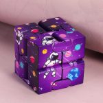 Oggetto scientifico a cubo con design spaziale, decorato con pianeti, stelle e un robot astronauta, ideale come decorazione o gioco educativo.