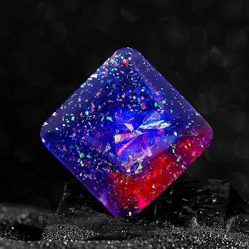 Pallina di vetro decorativa con glitter multicolore, perfetta come oggetto scientifico o decorativo, con effetto luminoso e brillante su sfondo nero.