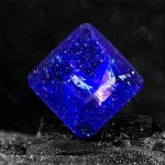 Pulsante cristallo di resina blu con riflessi iridescenti, perfetto come decorazione scientifica o oggetto da collezione.