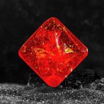 Oggetto scientifico decorativo in vetro rosso con riflessi dorati, perfetto come elemento di design o collezione.