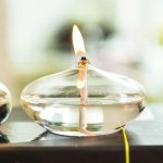 Vaso di vetro trasparente con candela accesa, creando un'atmosfera calda e accogliente. Perfetto come decorazione scientifica o oggetto di design per ambienti moderni.