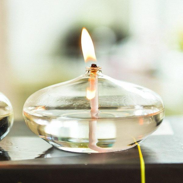 Vaso di vetro trasparente con candela accesa, creando un'atmosfera calda e accogliente. Perfetto come decorazione scientifica o oggetto di design per ambienti moderni.