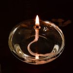 Candela scientifica accesa con fiammella visibile in un contenitore di vetro trasparente, ideale per decorazioni e oggetti scientifici.