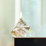Candela accesa sotto un cubo di vetro, creando un effetto visivo interessante e simbolico.
