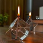 Vaso di cristallo con candela accesa, decorato con elementi scientifici, ideale come oggetto decorativo per appassionati di scienza e design innovativo.