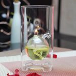 Vaso di vetro con sfera di liquido e fiamma accesa, oggetto scientifico decorativo, ideale per appassionati di chimica e scienza.
