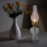 Vaso con fiori gialli e lampada a olio vintage accesa, decorazione scientifica e vintage.