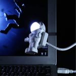 Modello di astronauta in miniatura con casco luminoso, decorazione scientifica per ambienti educativi e di design.