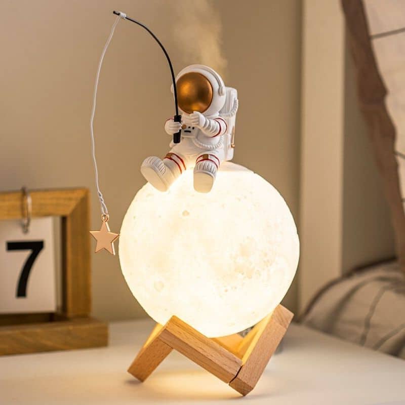 Luce da notte decorativa con astronauta che pesca dalla luna, perfetta per ambienti scientifici o per gli appassionati di spazio.