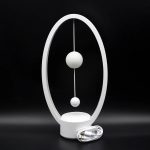 Orologio decorativo scientifico con due sfere sospese in un'ellisse bianca, ideale come decorazione moderna e originale.