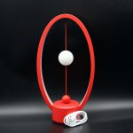 Orologio scientifico con struttura rossa e sfere bianche, ideale come decorazione da scrivania o oggetto di design ispirato alla scienza.