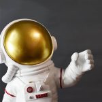 Modello di astronauta con casco dorato e tuta bianca, simbolo di esplorazione spaziale e curiosità scientifica. Perfetto come decorazione o oggetto da collezione.