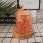 Cristalli di sale rosa dell'Himalaya in un barattolo di vetro su base di legno, decorativi e naturali, perfetti come oggetti di design e decorazioni scientifiche.