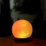 Palla di sale luminescente che emette una luce calda arancione, perfetta come decorazione scientifica o oggetto di design per ambienti moderni e accoglienti.
