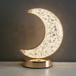Oggetto decorativo a forma di luna in cristallo con base dorata.