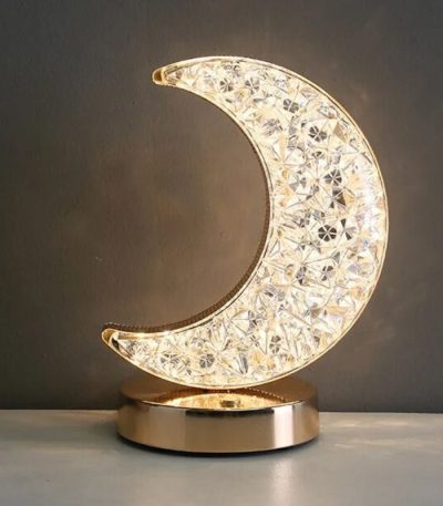 Oggetto decorativo a forma di luna in cristallo con base dorata.