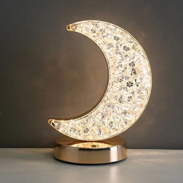 Oggetto decorativo a forma di luna in cristallo con base dorata.