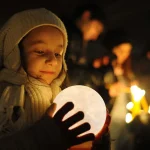 Bambina che tiene in mano una sfera luminosa a forma di luna, atmosfera calda e magica, sfondo notturno con altre luci soffuse, perfetta decorazione scientifica o oggetto di studio.