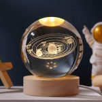 Modello del sistema solare in sfera di cristallo con pianeti e orbite dorate, su base in legno, decorazione scientifica elegante.