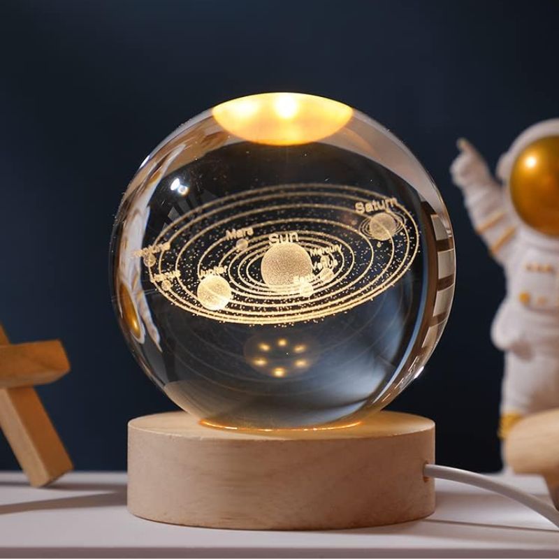 Modello del sistema solare in sfera di cristallo con pianeti e orbite dorate, su base in legno, decorazione scientifica elegante.