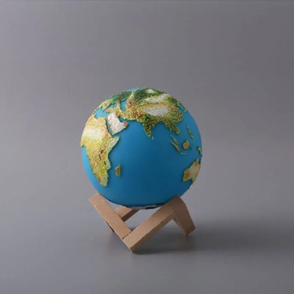 Modello in miniatura della Terra su supporto di legno, rappresenta il nostro pianeta con continenti e oceani dettagliati, ideale come decorazione scientifica.