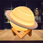 Saturno in miniatura con anelli dettagliati, posizionato su supporto in legno, decorazione scientifica originale e affascinante.