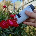 Lente di ingrandimento portatile in uso su fiori rossi, ideale per osservazioni scientifiche dettagliate all'aperto.