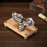 Motore elettrico in miniatura con componenti in metallo e vetro, posizionato su una base di legno, perfetto come oggetto decorativo o per progetti scientifici.