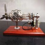 Motore a vapore in miniatura con componenti metallici e tubi di vetro.