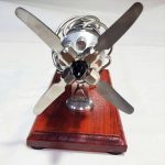 Modello di motore a vento scientifico con pale in metallo e base in legno, esempio di oggetto decorativo e didattico per appassionati di scienza.